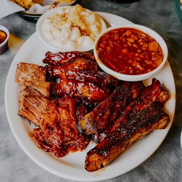 A plate of Sammy Sue's BBQ ribs, pulled pork, chicken wings, baked beans, and mac and cheese.